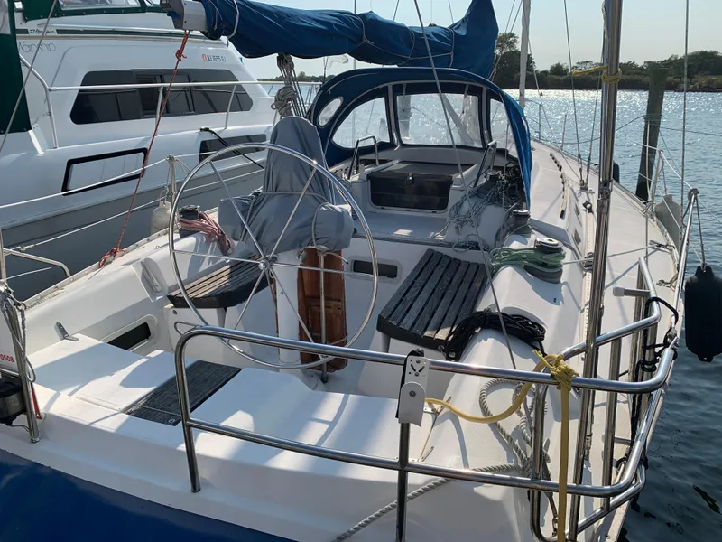 Slide: The Image of 1985 Hunter Legend 40 sailboat docked, featuring a spacious cockpit and steering wheel. - 29