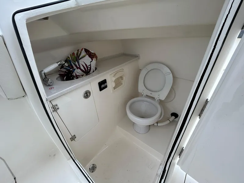 Slide: The Image of 2022 Cobia 240 Dual Console boat interior with compact marine toilet and sink. - 15