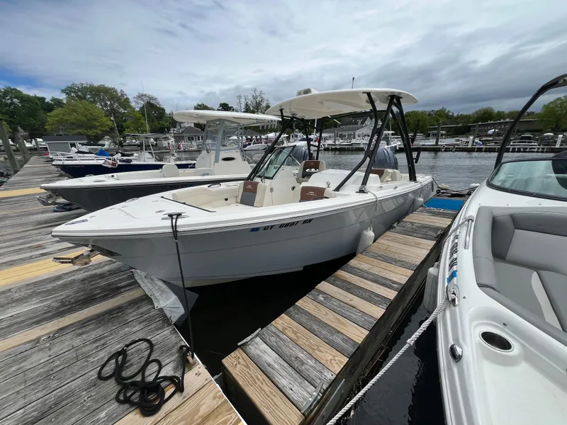 Slide: The Image of 2022 Cobia 240 Dual Console boat docked at marina. - 2