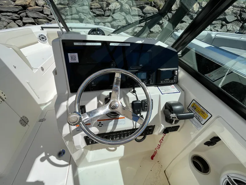 Slide: The Image of 2022 Cobia 240 Dual Console boat cockpit with steering wheel and controls. - 27