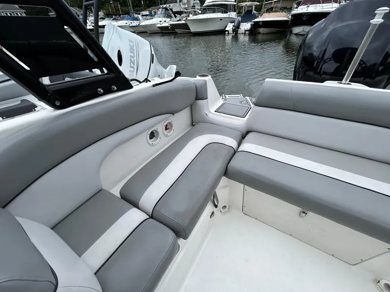 Slide: The Image of 2021 NauticStar 243 DC boat interior with gray seating, docked at marina. - 20