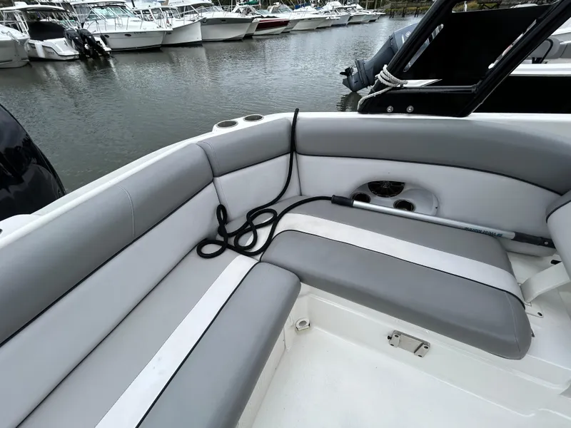 Slide: The Image of 2021 NauticStar 243 DC boat interior with gray seating, docked at marina. - 21