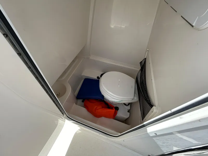 Slide: The Image of 2021 NauticStar 2602 Legacy boat interior with toilet and storage area. - 10