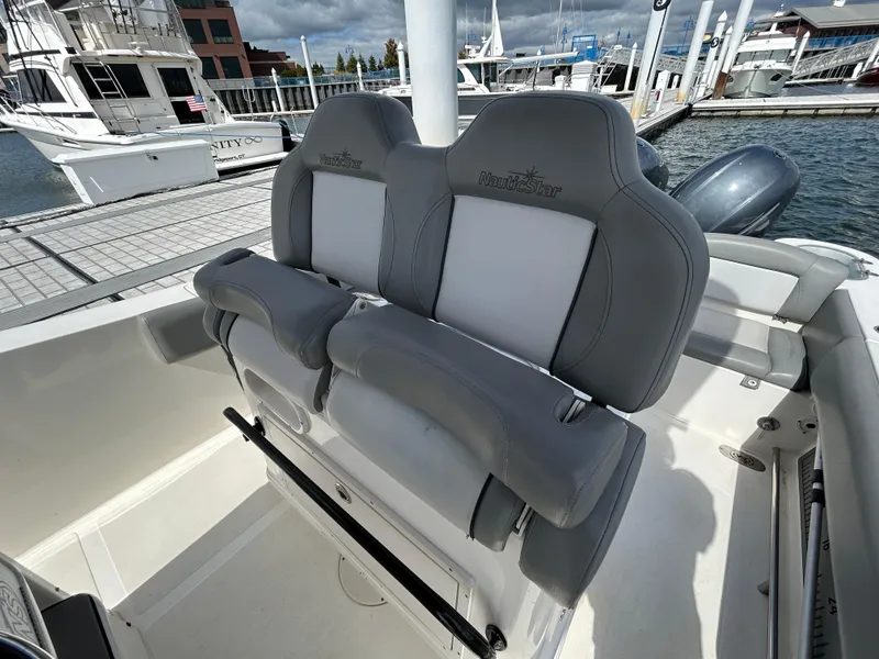 Slide: The Image of 2021 NauticStar 2602 Legacy boat seats at marina, featuring sleek gray upholstery. - 14