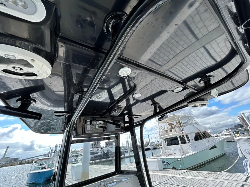 Slide: The Image of 2021 NauticStar 2602 Legacy boat interior with sleek black canopy at marina. - 15