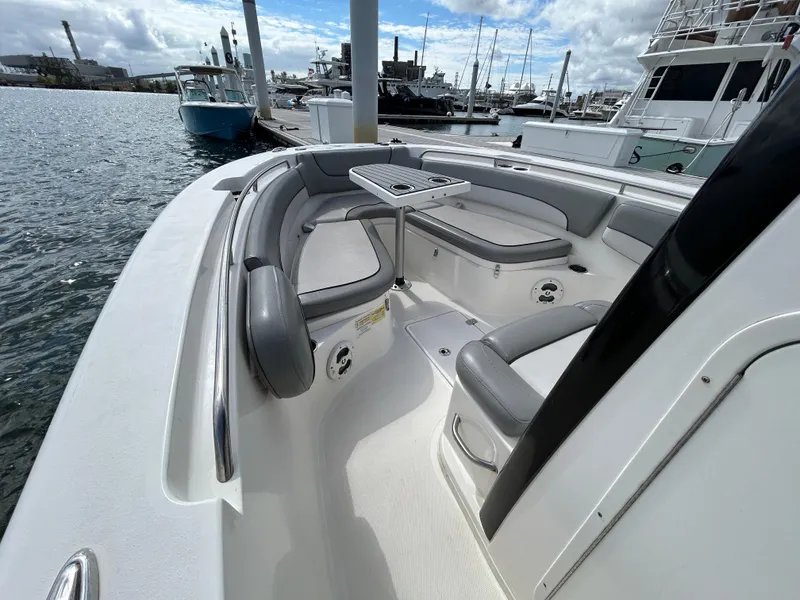 Slide: The Image of 2021 NauticStar 2602 Legacy boat interior with seating and table in marina. - 16