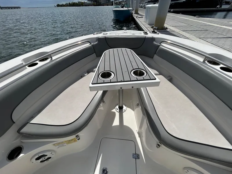 Slide: The Image of 2021 NauticStar 2602 Legacy boat interior with seating and table, docked by the water. - 17