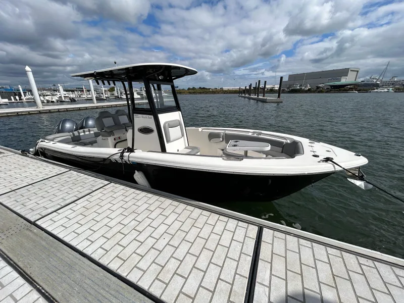 Slide: The Image of 2021 NauticStar 2602 Legacy boat docked at marina under cloudy sky. - 3