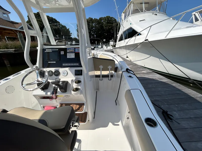 Slide: The Image of 2021 Tidewater 232 LXF boat interior at dock, featuring steering console and seating. - 14
