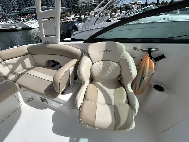 Slide: The Image of 2022 NauticStar 243 DC boat interior with beige seating at marina. - 13