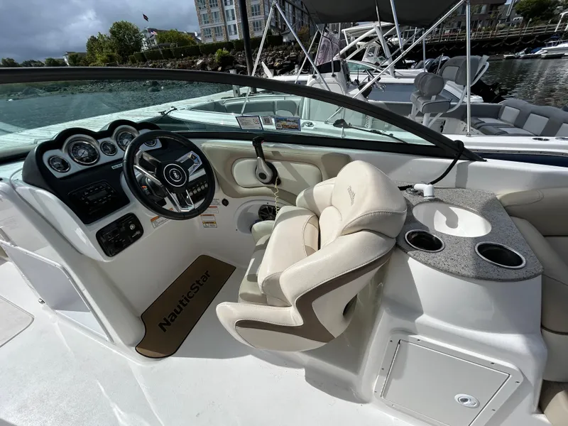 Slide: The Image of 2022 NauticStar 243 DC boat interior with steering wheel and seating area. - 14
