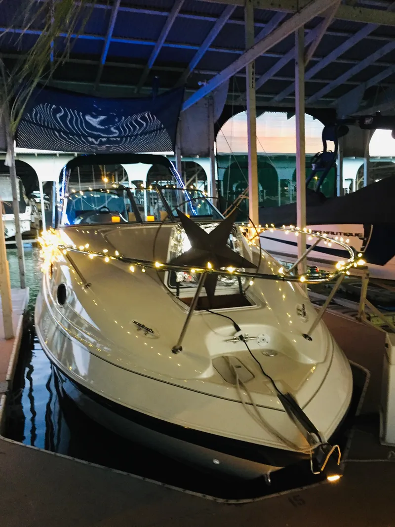 Slide: The Image of 1997 Regal Commodore 242 boat docked, adorned with string lights, under a covered marina. - 11
