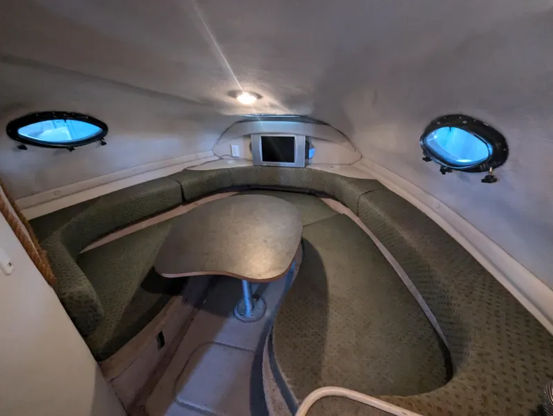 Slide: The Image of 1997 Regal Commodore 242 cabin interior with seating and table, featuring porthole windows. - 6