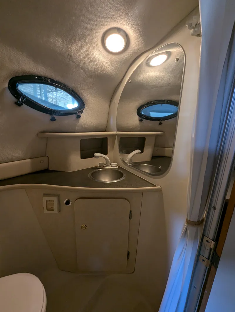 Slide: The Image of 1997 Regal Commodore 242 boat bathroom with sink, mirror, and porthole windows. - 7