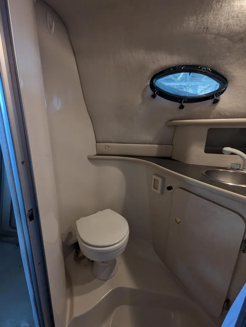 Slide: The Image of 1997 Regal Commodore 242 boat bathroom with toilet, sink, and porthole window. - 8