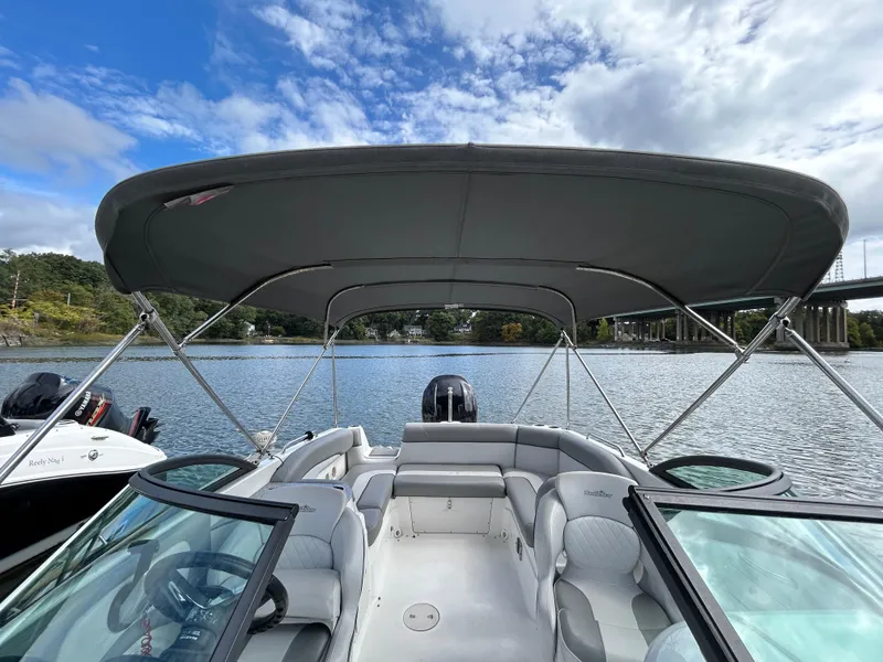 Slide: The Image of 2022 NauticStar 243 DC boat with canopy on a calm river under a blue sky. - 23