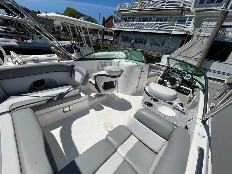 Slide: The Image of 2022 NauticStar 243 DC boat interior with seating and steering wheel, docked at marina. - 27