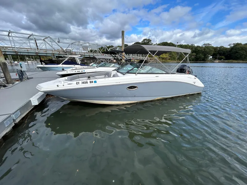 Slide: The Image of 2022 NauticStar 243 DC boat docked on a calm river under cloudy skies. - 3