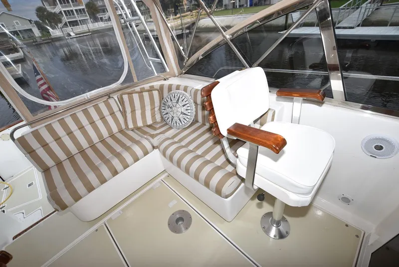 Slide: The Image of Interior of 1999 Legacy 34 Express boat with striped seating and captain's chair. - 11