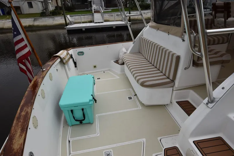 Slide: The Image of 1999 Legacy 34 Express boat deck with striped seating and a turquoise cooler. - 2
