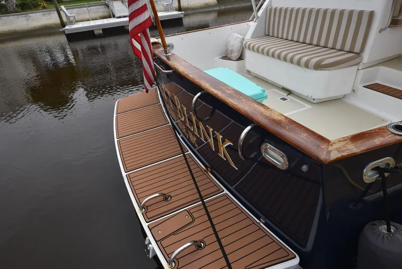 Slide: The Image of 1999 Legacy 34 Express boat with wooden deck and American flag at dock. - 3
