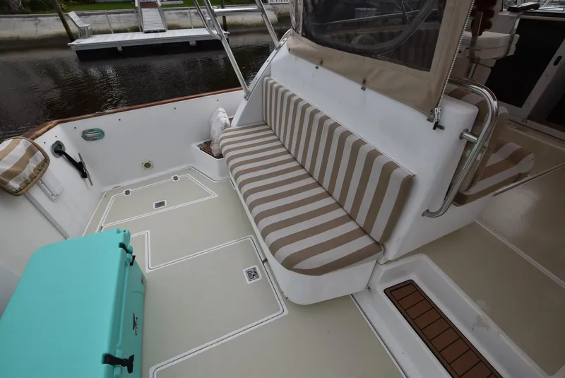 Slide: The Image of 1999 Legacy 34 Express boat interior with striped seating and teal cooler. - 4