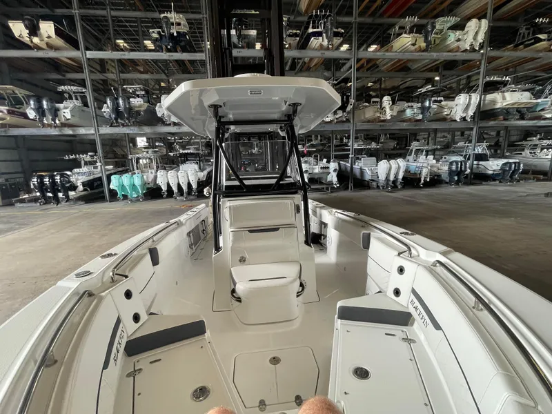 Slide: The Image of 2023 Blackfin 252 CC boat interior in storage facility, showcasing seating and console. - 22