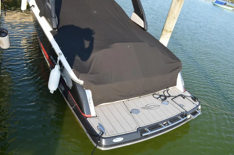 Slide: The Image of 2020 Chaparral 257 SSX boat with black cover docked on water. - 3