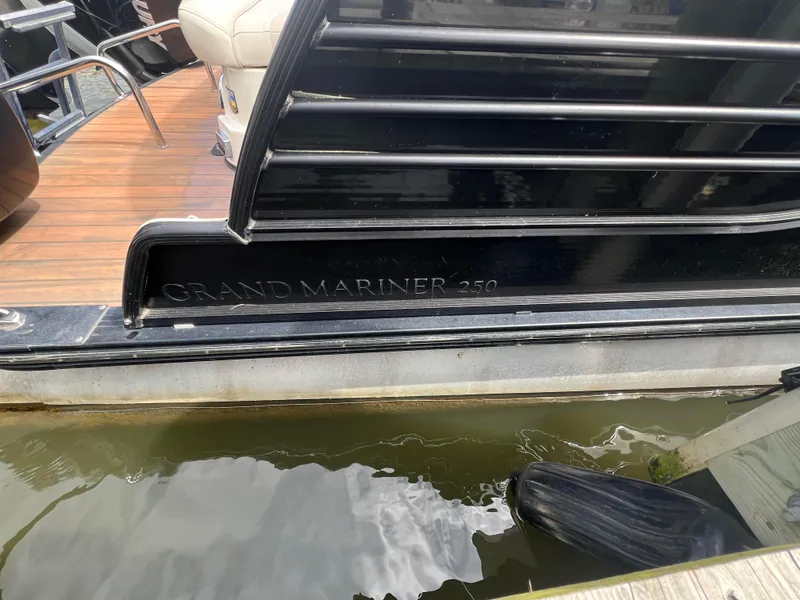 Slide: The Image of 2015 Harris FloteBote Grand Mariner SL 250 docked, showcasing sleek design and wooden deck. - 1