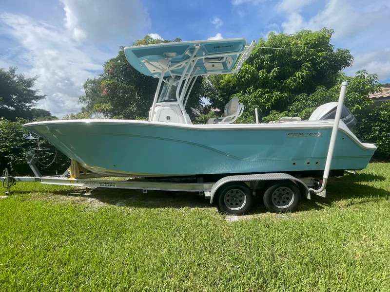 Slide: The Image of 2021 Sea Fox 248 Commander boat on trailer, parked on grass under a cloudy sky. - 0