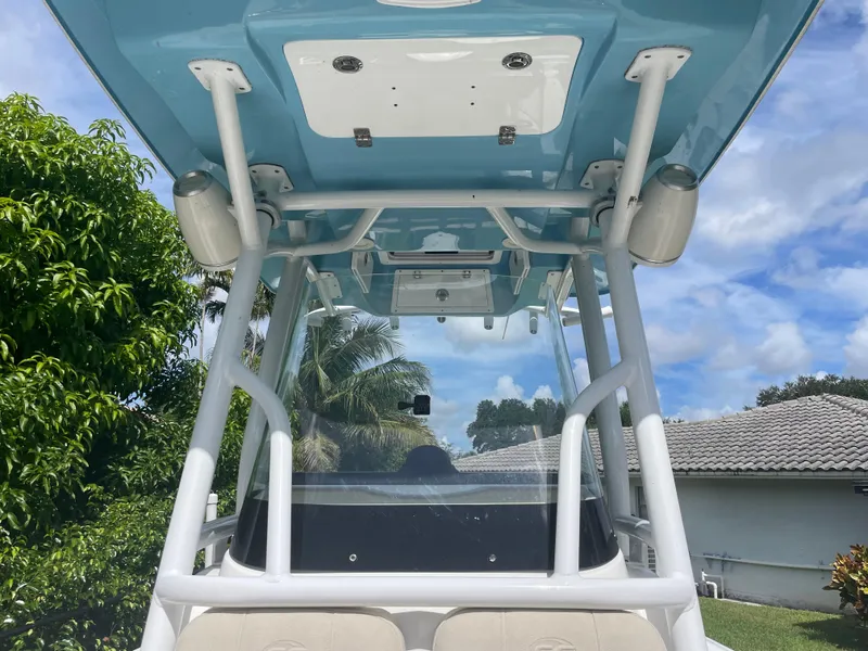 Slide: The Image of 2021 Sea Fox 248 Commander boat with blue T-top and white frame, parked outdoors. - 7