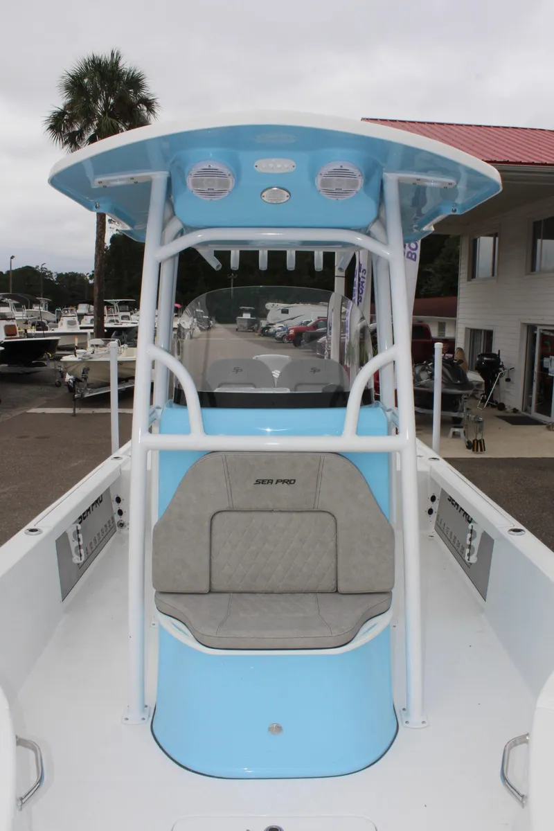 Slide: The Image of 2025 Sea Pro 250 Bay boat with blue console and seating, docked near palm tree. - 36