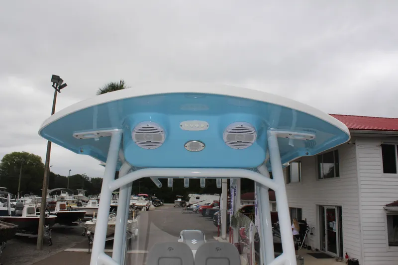 Slide: The Image of 2025 Sea Pro 250 Bay boat with blue T-top and speakers, docked near buildings. - 38