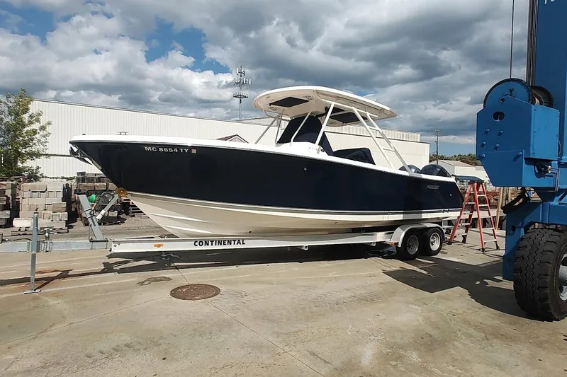 Slide: The Image of 2015 Pursuit S 280 Sport boat on trailer, parked outdoors under cloudy sky. - 1