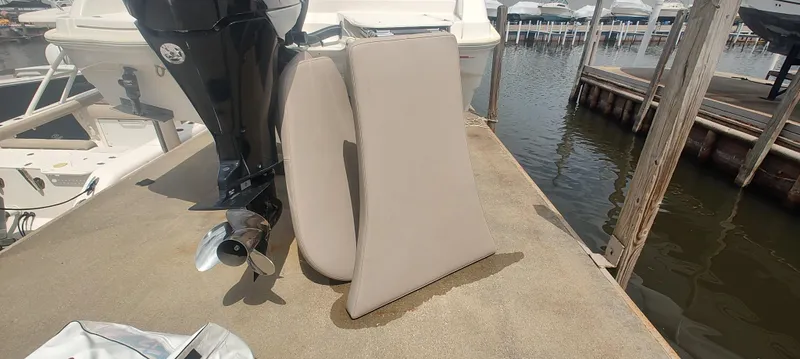 Slide: The Image of 2015 Pursuit S 280 Sport boat engine and cushions on dock by water. - 11