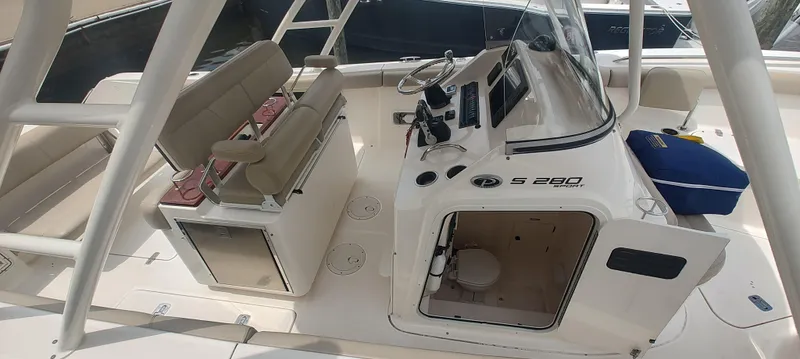 Slide: The Image of 2015 Pursuit S 280 Sport boat interior with helm, seating, and storage. - 13