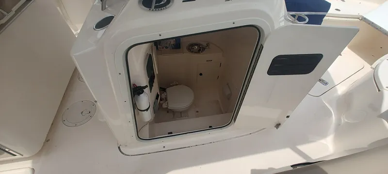 Slide: The Image of 2015 Pursuit S 280 Sport boat interior with open door revealing compact bathroom. - 14