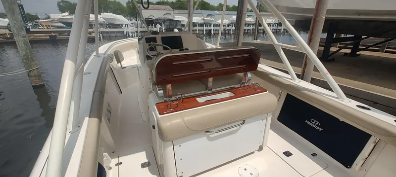 Slide: The Image of 2015 Pursuit S 280 Sport boat interior with seating and storage, docked at a marina. - 16
