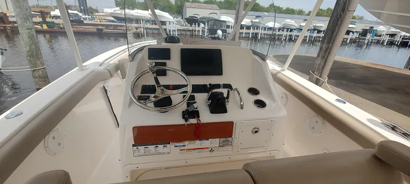 Slide: The Image of 2015 Pursuit S 280 Sport boat helm with steering wheel and controls at marina. - 17