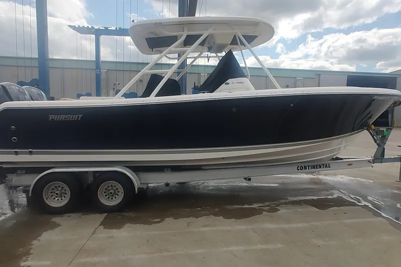 Slide: The Image of 2015 Pursuit S 280 Sport boat on trailer, parked outdoors under cloudy sky. - 2
