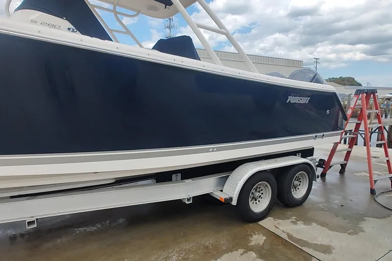 Slide: The Image of 2015 Pursuit S 280 Sport boat on trailer, parked outdoors under cloudy sky. - 31