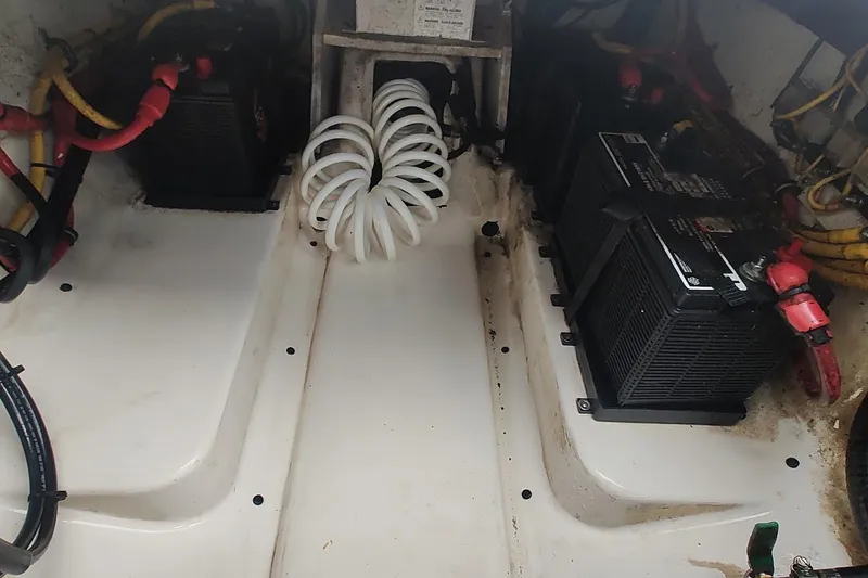 Slide: The Image of 2015 Pursuit S 280 Sport boat battery compartment with wiring and coiled hose. - 46