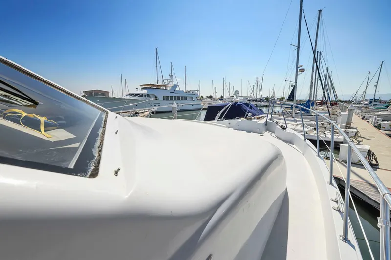 Slide: The Image of 2001 Hatteras 75 Sport Deck yacht docked in a marina under clear blue skies. - 42