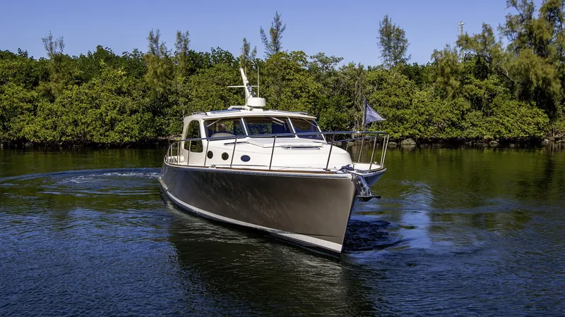 Slide: The Image of 2017 Palm Beach PB42 yacht cruising on a serene waterway with lush greenery. - 6