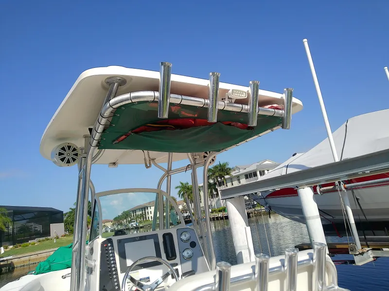 Slide: The Image of 2004 Trophy 2503 Center Console boat with T-top and rod holders, docked by waterfront homes. - 11