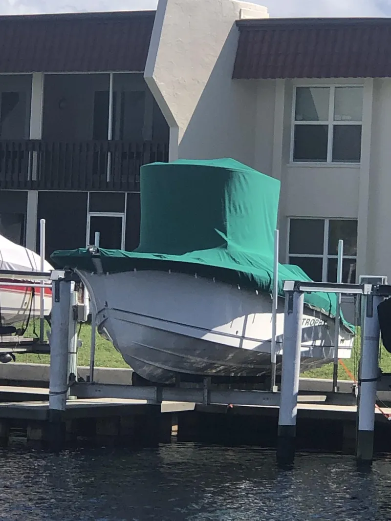 Slide: The Image of 2004 Trophy 2503 Center Console boat covered, docked near waterfront building. - 2