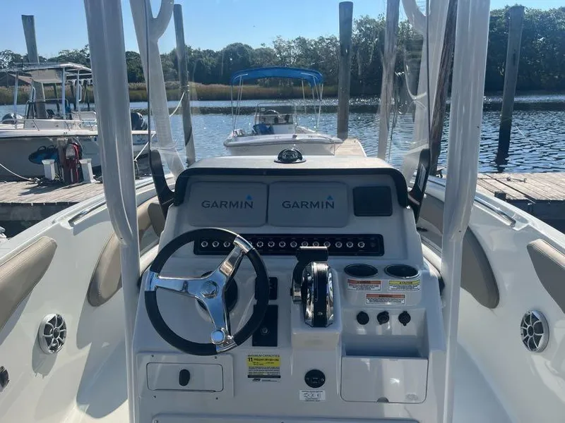 Slide: The Image of 2023 Crownline 220 CC Finseeker boat dashboard with Garmin navigation, docked by the water. - 2