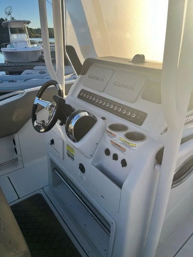 Slide: The Image of 2023 Crownline 220 CC Finseeker boat dashboard with steering wheel and Garmin displays. - 3