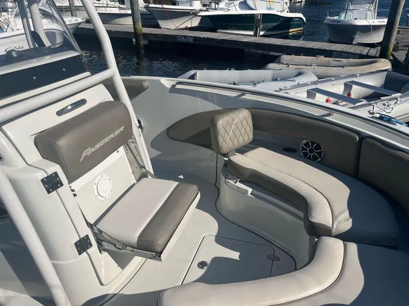 Slide: The Image of 2023 Crownline 220 CC Finseeker boat interior with cushioned seating at a marina. - 5