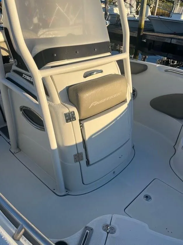 Slide: The Image of 2023 Crownline 220 CC Finseeker boat interior, featuring helm seating and storage. - 6